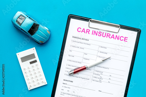 Car insurance concept with form, car toy and calculator on blue background top view