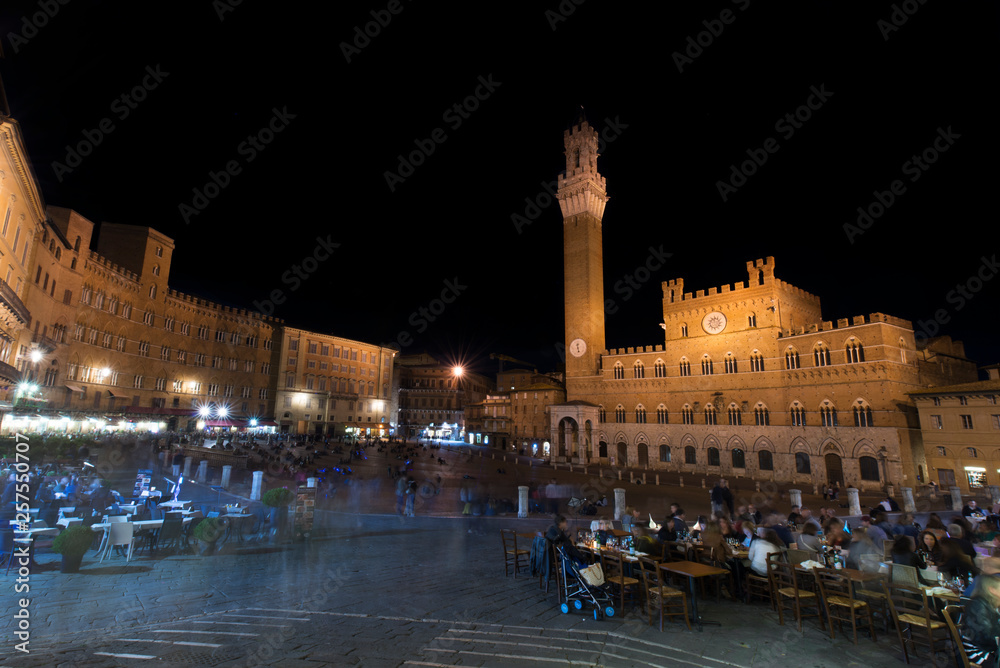 Tourists in Piazza del Campo by night, Siena, Italy. The historic centre of Siena. UNESCO World Heritage Site