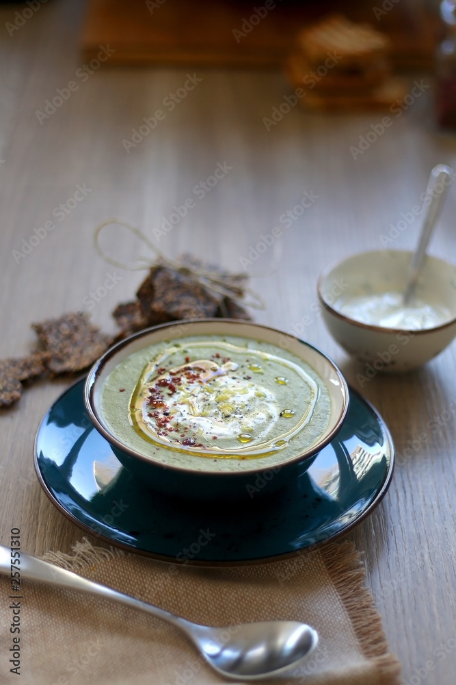Creamy vegetable soup with kale, cabbage, celery and millet, decorated with olive oil, yoghurt sauce and chilli flakes. Served with seed crackers and lemony yoghurt sauce. Selective focus. Creamy vegetable soup with kale, cabbage, celery and millet, decorated with olive oil, yoghurt sauce and chilli flakes. Served with seed crackers and lemony yoghurt sauce. Selective focus.