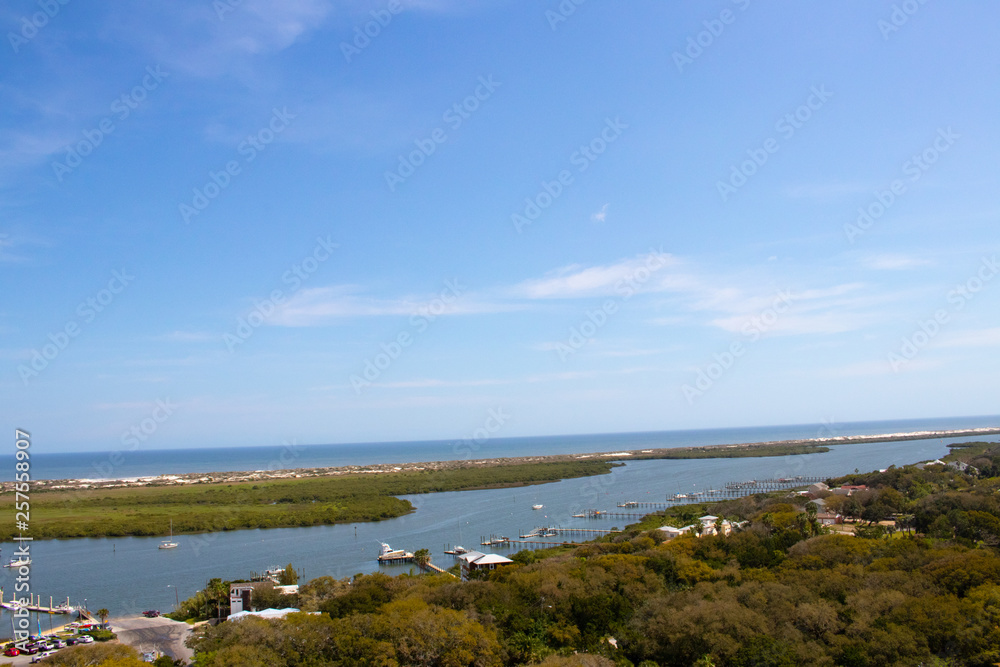Looking from a high point down into an inlet with islands, a blue sky and whispy white clouds
