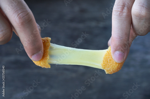 Hand is holding a stretch mozzarella cheese ball.