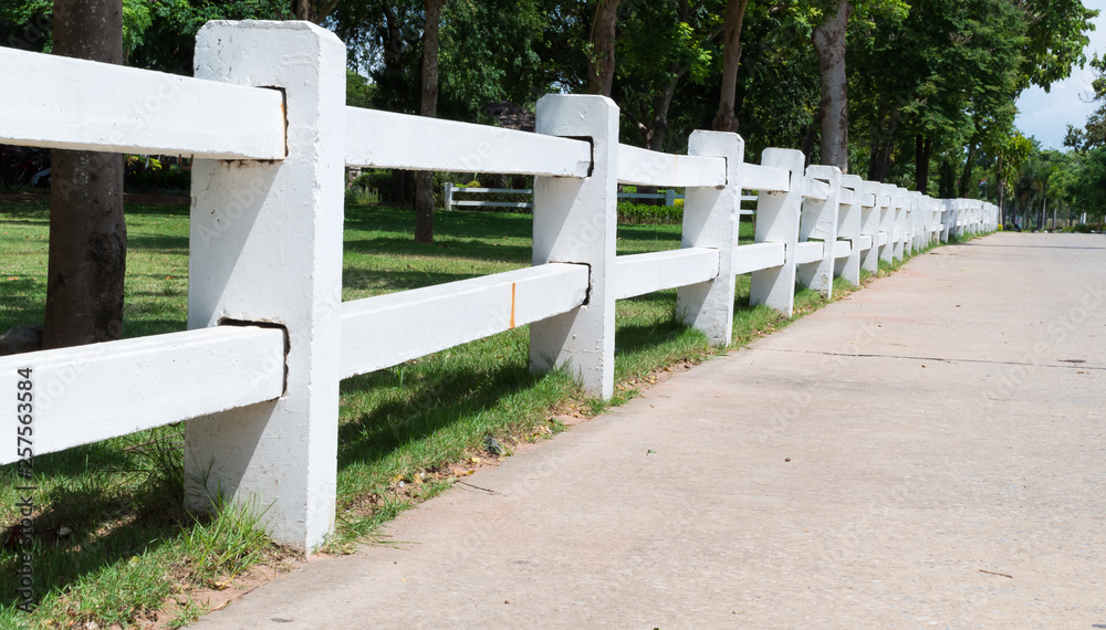 Row of white fence along the concrete road
