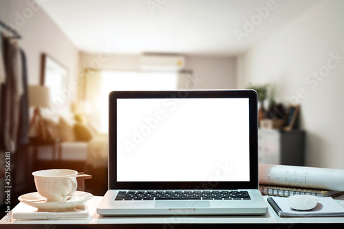 Front view of cup and laptop, smartphone, and tablet on table in office and background 
