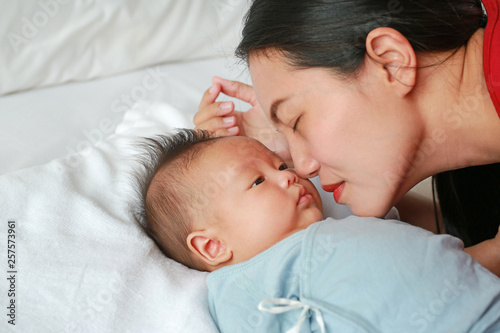 Close up mother kissing newborn baby boy lying on the bed.
