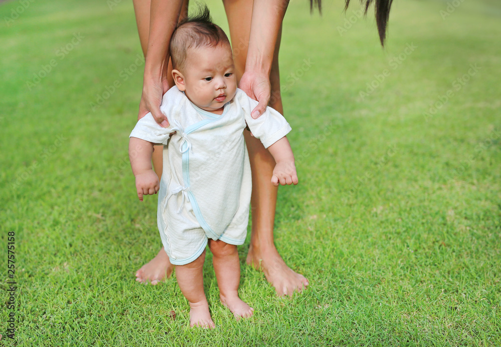 First steps of newborn baby in the green grass garden. First steps of newborn baby in the green grass garden.