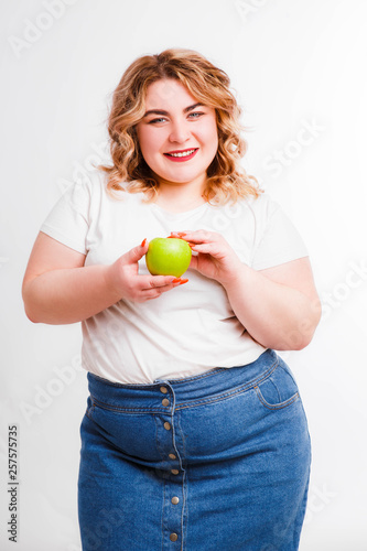 Beautiful fat young woman with bright emotions on a light gray background. Concept of diet. Space for text.