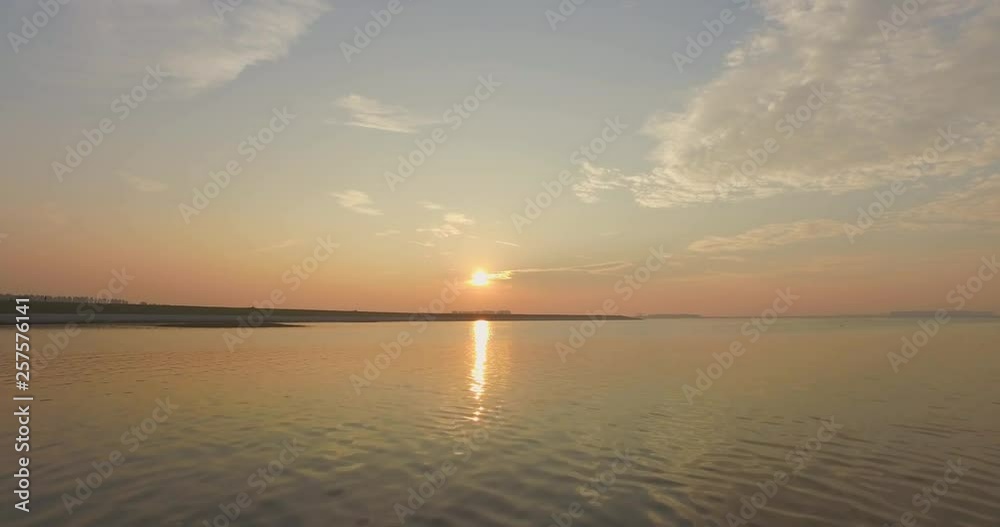 Aerial: The dykes and shoreline of the Oosterschelde, the Netherlands. Filmed during a hazy sunset.