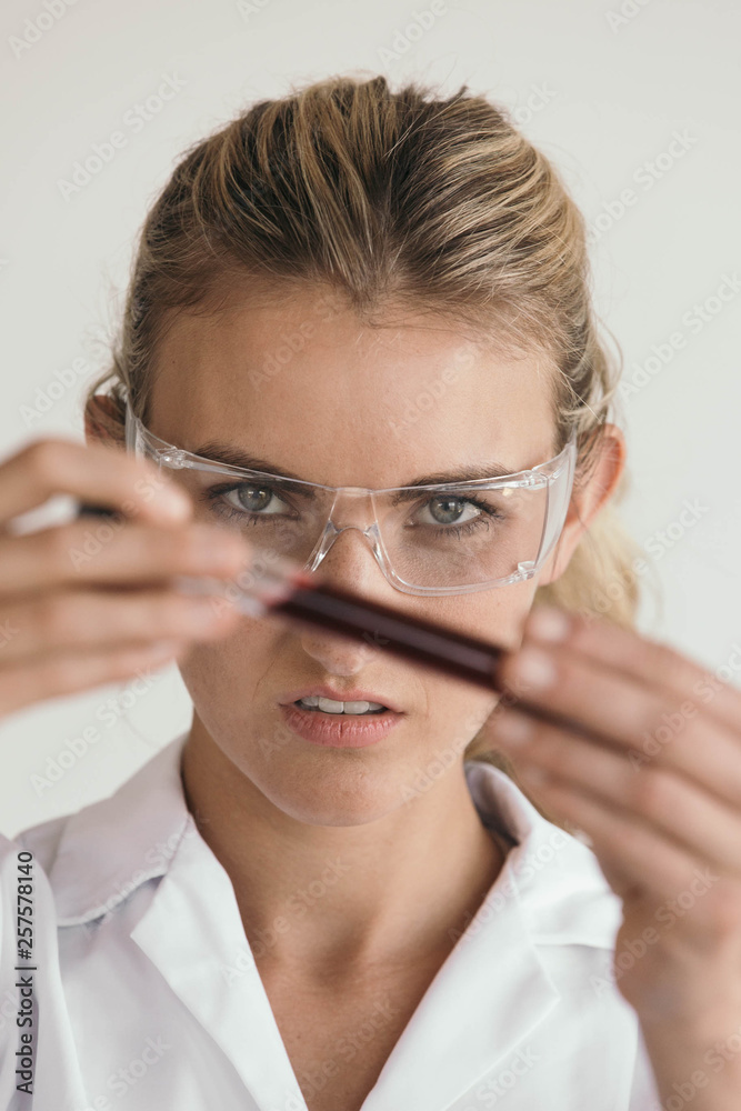 Female doctor or scientist inspecting a blood vial Female doctor or scientist inspecting a blood vial