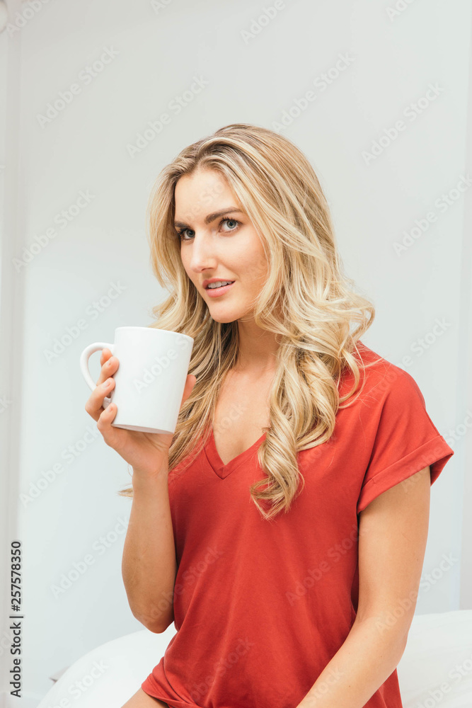 Blonde drinking coffee, tea or soup from a white cup Blonde drinking coffee, tea or soup from a white cup