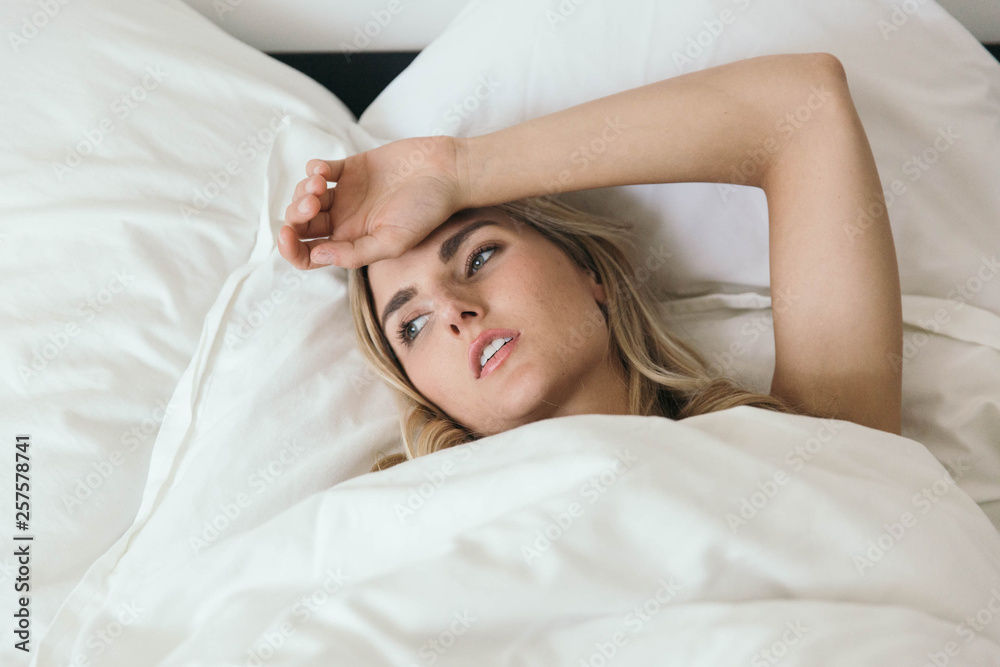 Fototapeta premium blonde caucasian waking up grumpy with a headache, in a bad mood