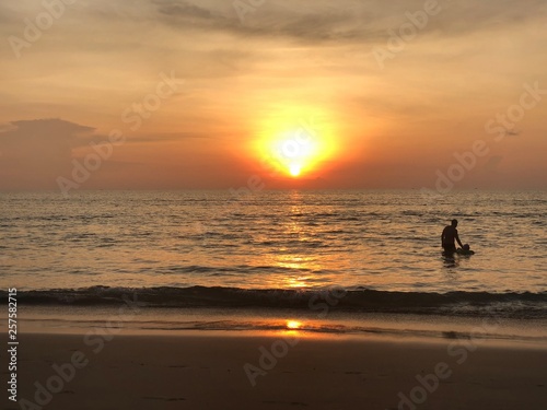 the sun sets on the horizon where the sea joins the sky. people-adult and child-swim in the sea and enjoy the Golden sunset on the beach