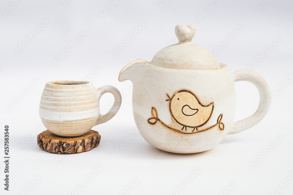 white teapot and ceramic stoneware cup with white background