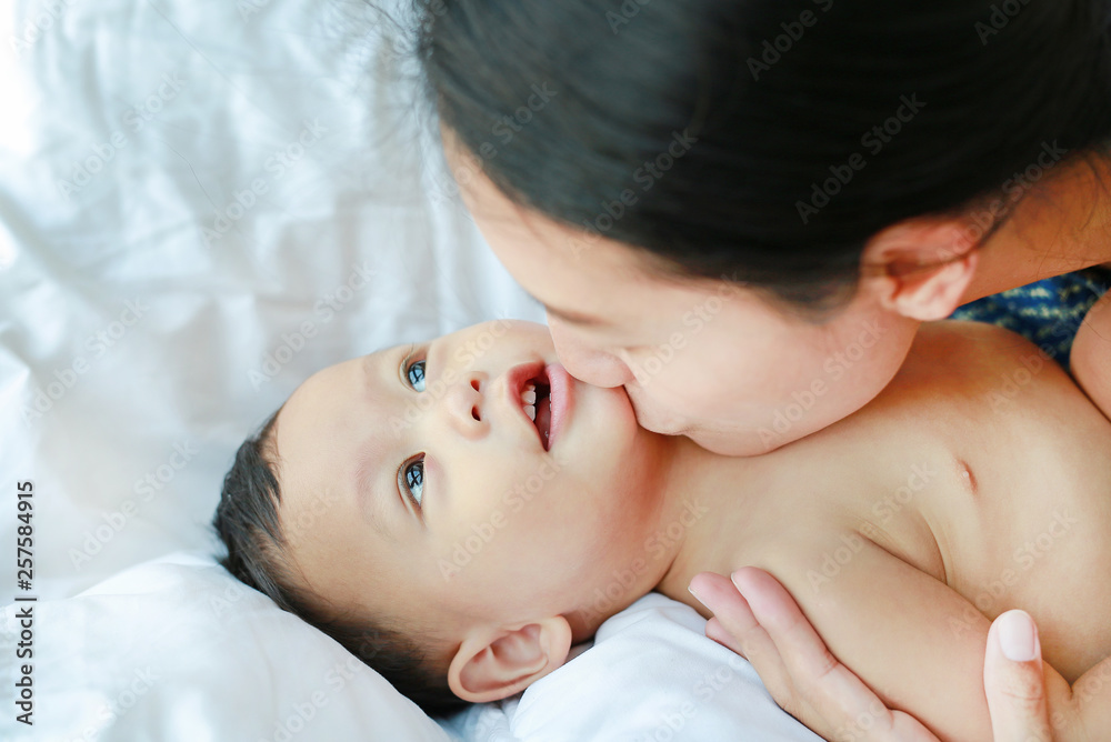 Close-up Asian mom playing and kissing her little baby boy on the bed. Close-up Asian mom playing and kissing her little baby boy on the bed.