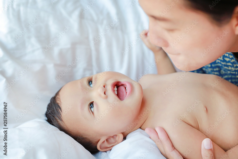 Asian Mother is playing with her little baby boy on the bed. Asian Mother is playing with her little baby boy on the bed.