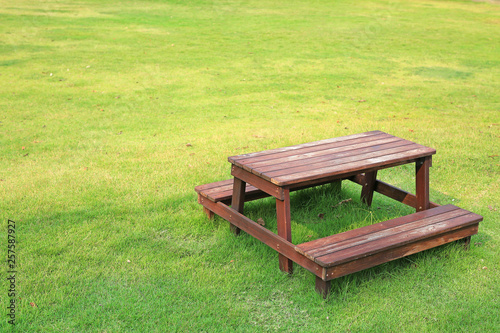 Wooden table and chairs set on green lawn in the garden.