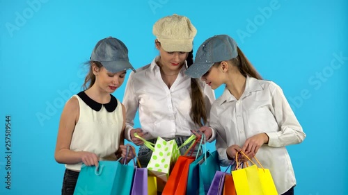 Three girl shopper looks in shopping paper bagand and happy . Blue background photo