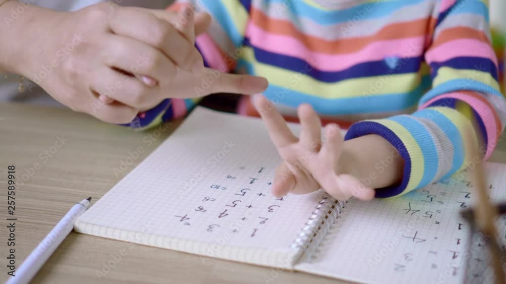 Mom teaching her daughter to writing in the book on the table, Educational concept for school Mom teaching her daughter to writing in the book on the table, Educational concept for school