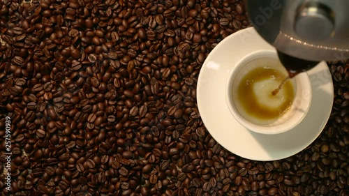 Coffee cup and coffee beans. A white cup of evaporating coffee on the table with roasted bean. Slow Motion coffee pour.