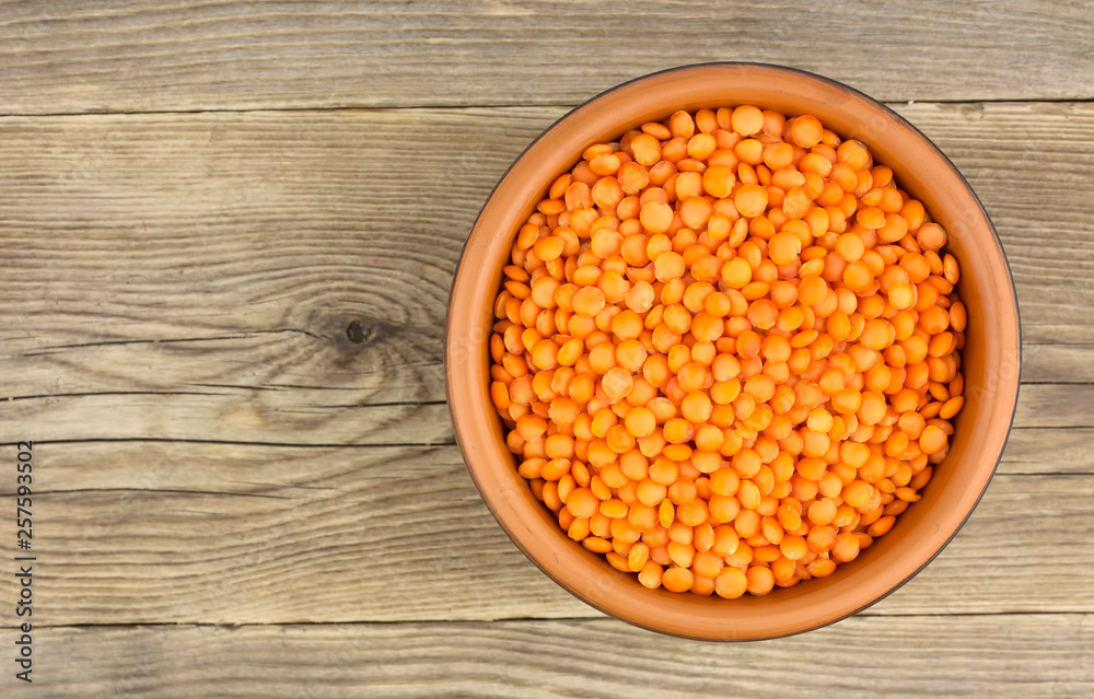 Red lentils in plate on wooden background Red lentils in plate on wooden background