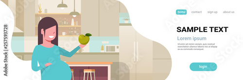 happy pregnant woman holding green apple pregnancy and motherhood concept girl eating healthy fresh fruit food flat portrait modern kitchen interior horizontal copy space