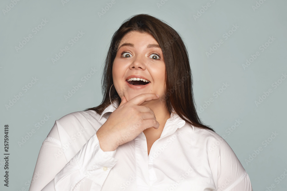 No way. Portrait of attractive young chubby female in formal wear opening mouth widely and touching chin, expressing astonishment while listening to incredible story. Human facial expressions No way. Portrait of attractive young chubby female in formal wear opening mouth widely and touching chin, expressing astonishment while listening to incredible story. Human facial expressions