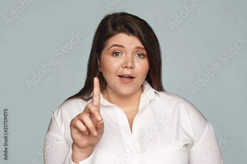 Wait a minute! Emotional indignant young plus size female saying No, showing fore finger, expressing her point of view or dissent, raising objection, being strongly disagree. Selective focus
