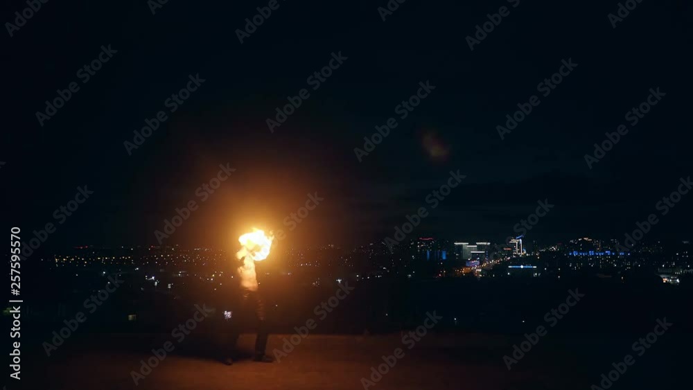 Young blond male plays with two fire torches, spins them at night on black background. Young blond male plays with two fire torches, spins them at night on black background.