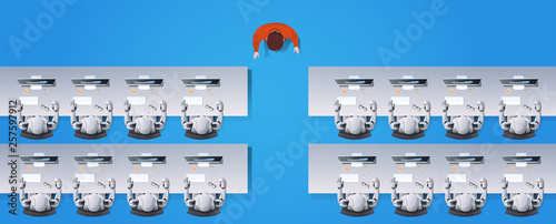 man teacher teaching humanoid robots group sitting at desks in classroom robotic school artificial intelligence concept flat top angle view horizontal