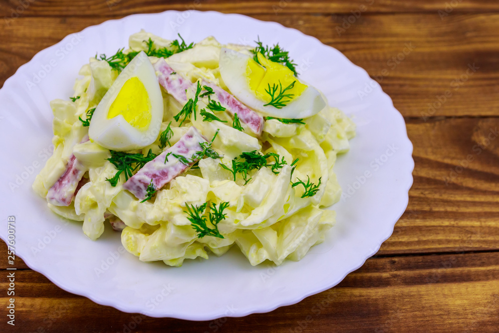 Salad with chinese cabbage, onion, sausage, eggs and mayonnaise on wooden table Salad with chinese cabbage, onion, sausage, eggs and mayonnaise on wooden table