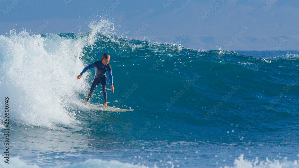 Stoked surfer having fun riding and looking around the scenic sunny seaside.