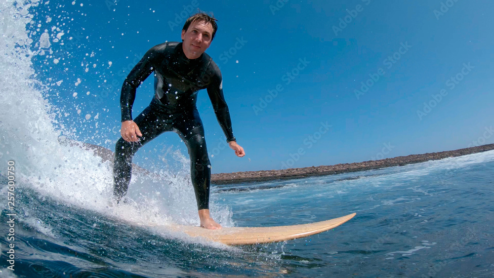 CLOSE UP: Stoked surfboarder smiling and riding a wave to the coast in Spain. CLOSE UP: Stoked surfboarder smiling and riding a wave to the coast in Spain.