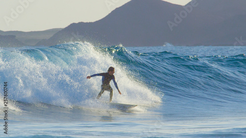 Pro surfboarder riding big barrel ocean waves in beautiful Fuerteventura.