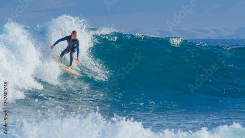 Surfer on summer vacation enjoying sunny day surfing in clear ocean water. © helivideo