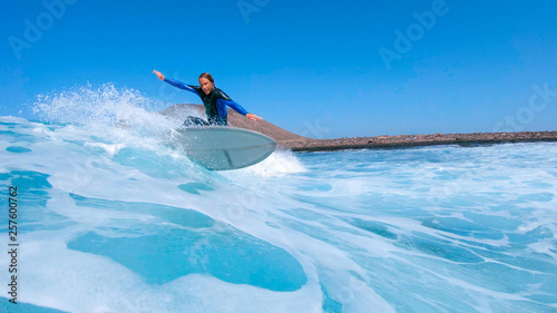 LOW ANGLE: Pro male surfer carves a beautiful turquoise wave near scenic Lobos.