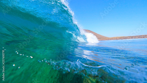 CLOSE UP Big barrel wave rushing towards peaceful rocky tropical island in Spain