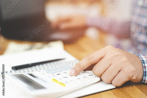 close up hand view of business woman using calculator on her and mobile smart phone press button keyboard used for mathematical calculations. documents on table. concept calculate account finance 