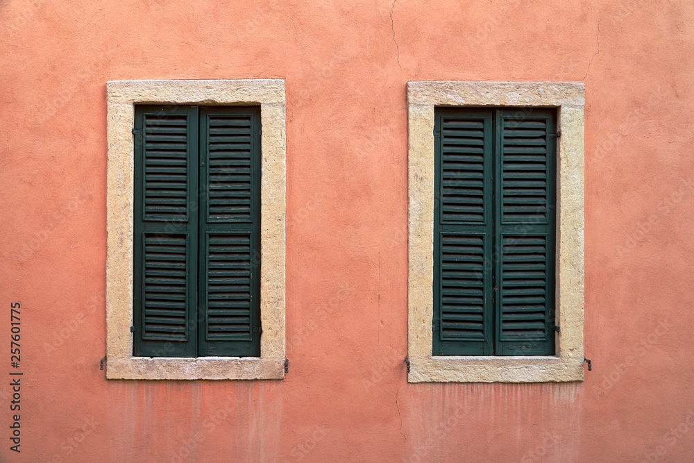 Two windows with closed shutters.