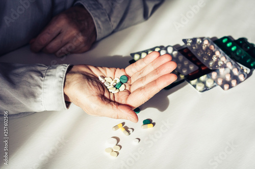 Medicine pills or capsules with old woman’s hands on white background with copy space. Blister pack.