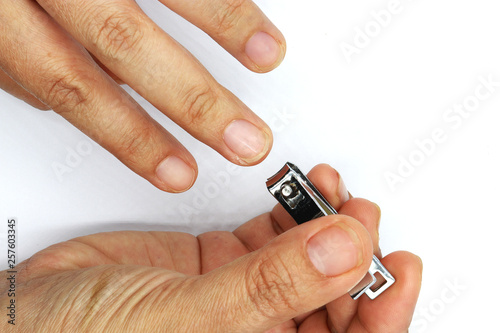 Woman cutting nails using nail clipper isolated on black background.