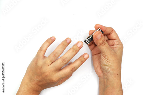 Woman cutting nails using nail clipper isolated on black background.