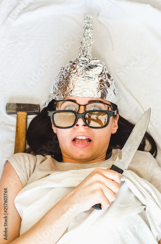 Paranoid woman wears foil hat and tries to protect herself with knife because of mental disease