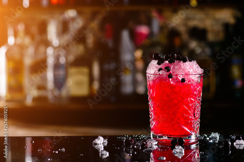 blackcurrant cocktail with ice on forward bar background