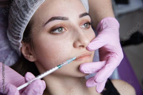 The doctor cosmetologist makes the Rejuvenating facial injections procedure for tightening and smoothing wrinkles on the face skin of a beautiful  young woman in a beauty salon.