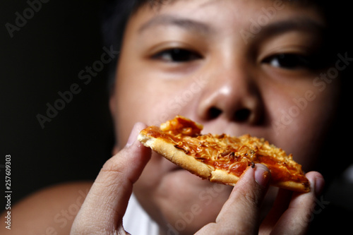 Young Asian boy eating a slice of pizza