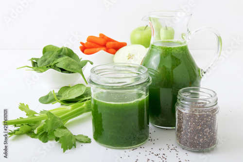 Vegetable smoothie, healthy organic juice made from celery, green apples, leaves of spinach and young carrot. Big pitcher and jar of green juice, small jar with chia seeds. Prevention of diabetes.
