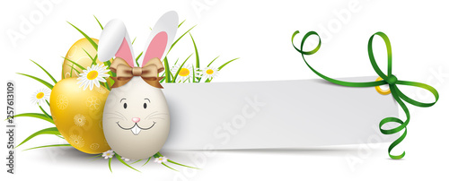Papierzettel mit grünen Schleife und Ostereiern mit einem Osterhasen