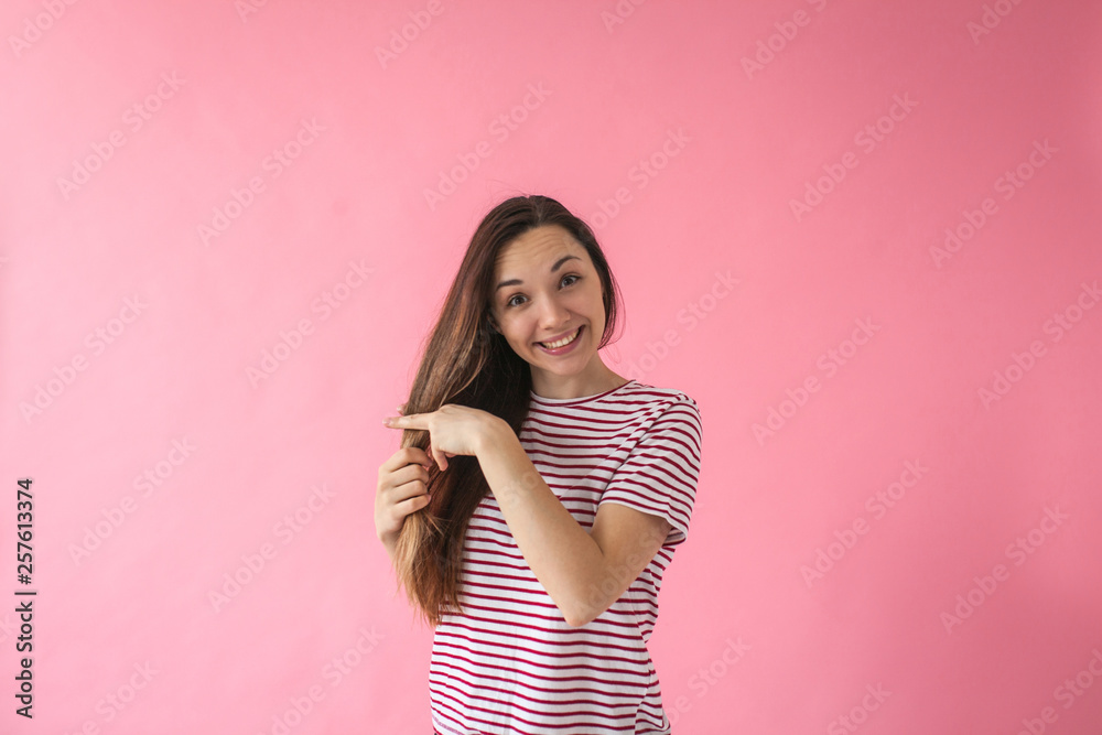 Portrait of a smiling brunette girl with long hair on a pink background. Portrait of a smiling brunette girl with long hair on a pink background.