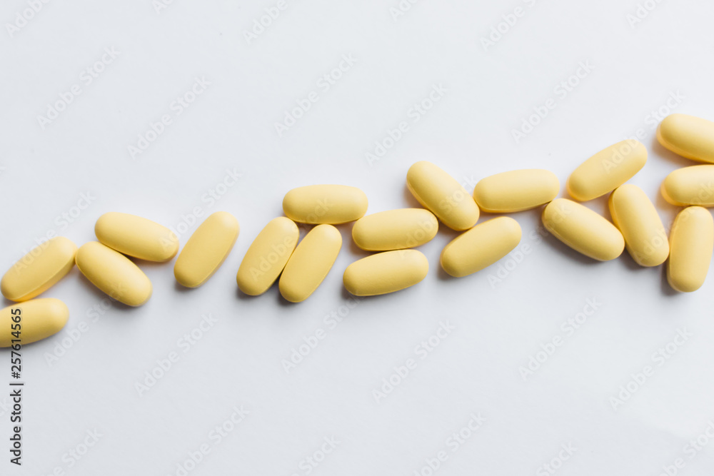 Scatterded yellow pills on white background Scatterded yellow pills on white background