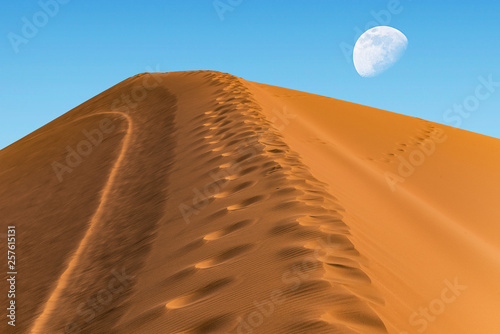 huge sand dune on the background of the sky with a moon on the horizon photo