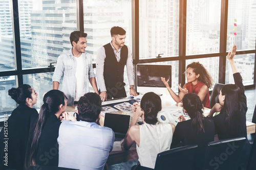 Successful team leader and business owner leading informal in-house business meeting. Business people working on laptops in foreground and glass reflections. Business and entrepreneurship concept